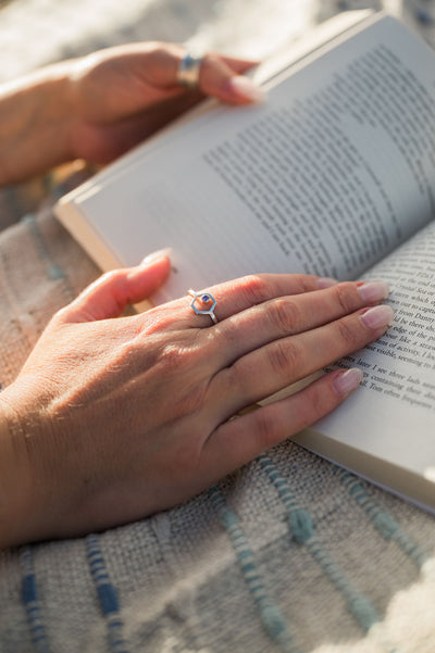 ladies hand wearing hexagon gemstone resting on an open book