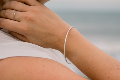 Woman wearing silver textured bangle and silver and gold ring