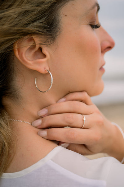 woman wearing silver hoop earrings and ring